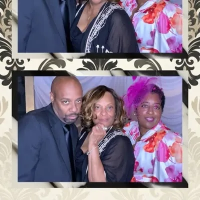 Three party guests in formal wear and a feather boa at a photo booth